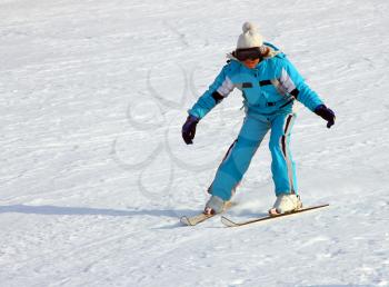 Little girl skiing downhill in winter equipment