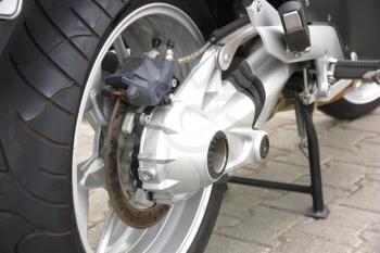 Black wheel of a motorcycle with the chromeplated muffler the rear view