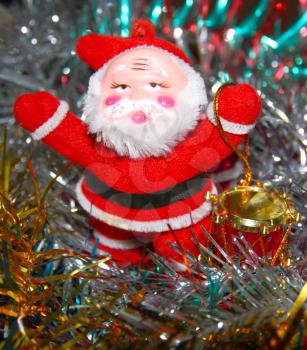 Doll of Santa Claus with a red drum against a tinsel