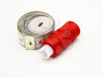 The coil of a red thread with centimeter on a white background