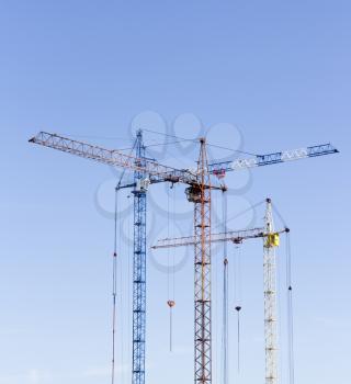 Industrial landscape with silhouettes of cranes on the sky background