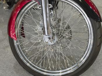 Beautiful nickel plated front wheel of a red motorcycle.
