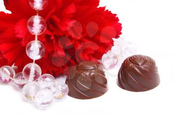 red flower and black chocolate on white background
