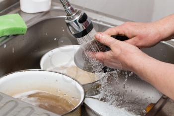 Woman washes spoons under a tap of water .