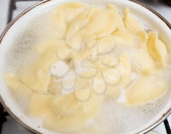 Vareniki with potatoes are cooked in a saucepan in the kitchen