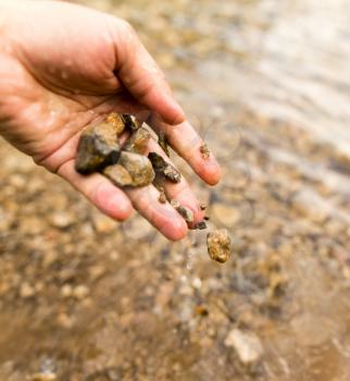 Small stones in the hand on the pond .