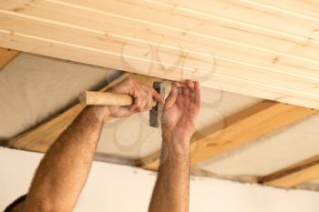 worker working on a wooden ceiling in the house .