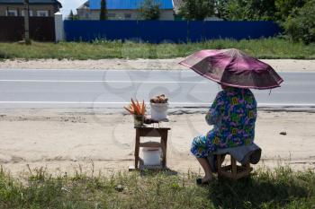 grandmother sells carrots and potatoes on the road