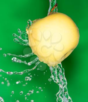 yellow apple in water on a green background