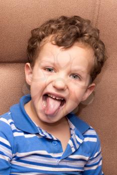 curly haired boy showing tongue
