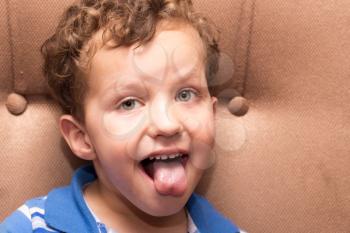 curly haired boy showing tongue