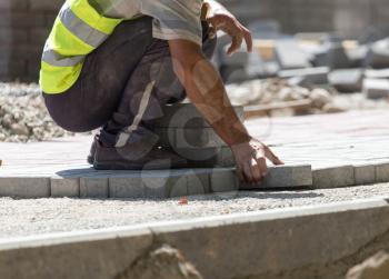 Worker puts sidewalk tile on the road