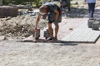Worker puts sidewalk tile on the road