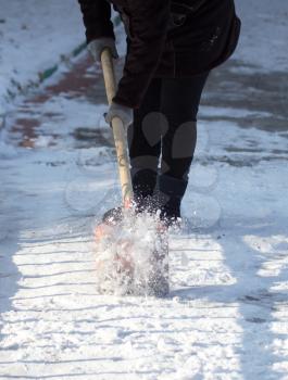 working woman cleans snow shovel in the nature