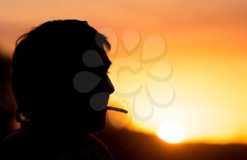 Silhouette of male smokers in the sunset