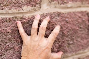 hand on the brick wall
