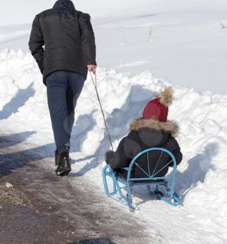 Dad rolls the child on a sled