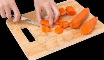 cook cuts carrots on a board on a black background