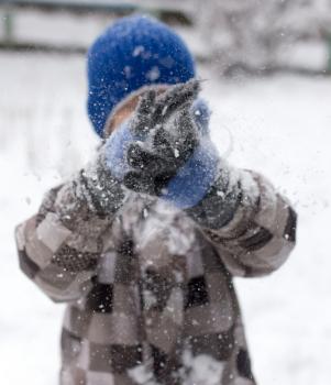 Boy playing with snow on nature in winter