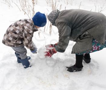 a boy with his grandmother playing in the snow .