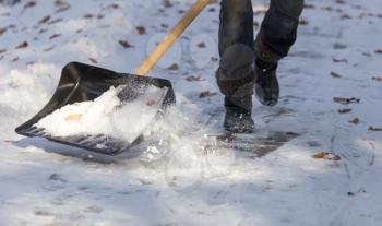 Worker cleans snow shovel in the nature .