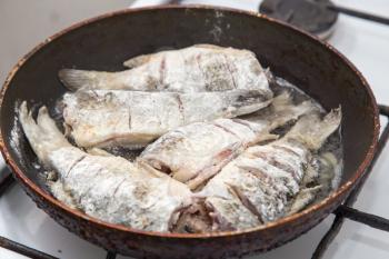 Fish carp is fried in a frying pan .