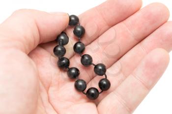Black beads in hand on a white background .