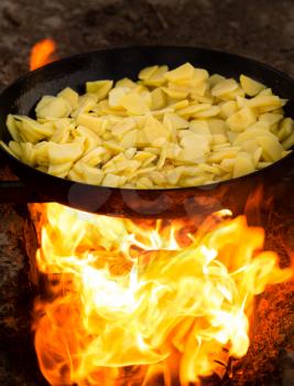 Potatoes fried in a frying pan in the open air .