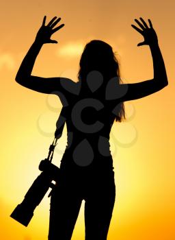 Silhouette of a girl photographer at sunset .