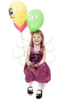 A laughing kid in red dress is playing with balloons; isolated on the white background