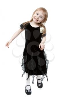 The little girl in a black suede dress hamming in the studio on a white background