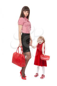 Fashionable Mom in red shoes and her little daughter with a beautiful handbag. Studio portrait, isolate on white.