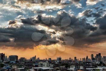 view of the city at sunset, the sun breaks through the clouds