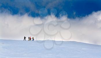 Four snowboarders go up the hill against the sky