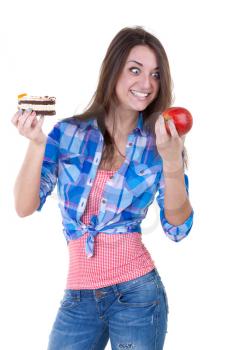 The girl eagerly looking at the apple and holding a cake. Isolate on white