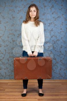 portrait of a beautiful girl with a suitcase in his hand on a retro background