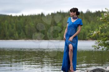 girl in a luxurious evening dress on the lake shows a slim leg