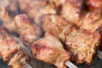Background of shish kebab on skewers on the grill with coals. Shallow depth of field.