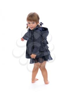 Little girl in a blue cloak with dots playfully turns the studio on a white background.