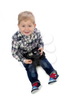 The three-year boy with a camera in hand sitting in the studio on a white background.