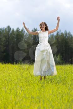 woman in a wedding dress jumping in a field