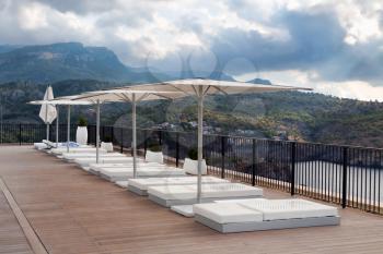 Place sun with sun beds and umbrellas on the background of mountains and gloomy clouds