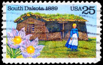 Royalty Free Photo of 1989 US Stamp Shows the State Flower, Pioneer Woman and Sod House on Grasslands, South Dakota State Centenary
