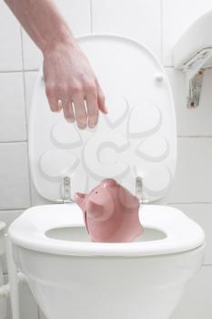 Royalty Free Photo of a Man Throwing a Piggy Bank in the Toilet