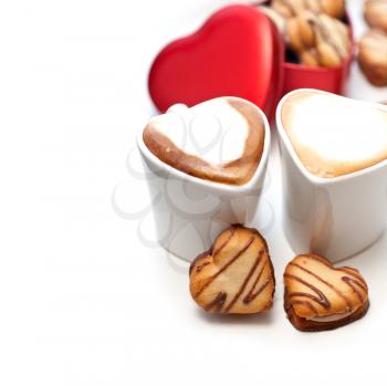 heart shaped cream cookies on red heart metal box and couple of cappuccino coffee cups