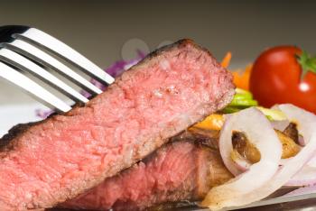 fresh juicy beef ribeye steak sliced ,with lemon and orange peel on top  and vegetable beside