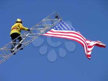Royalty Free Photo of a Fireman Climbing a Ladder to an American Flag