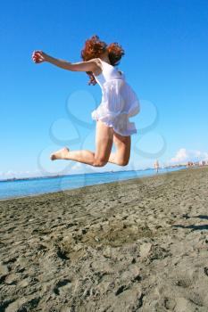 Royalty Free Photo of a Woman Jumping into the Air on the Beach