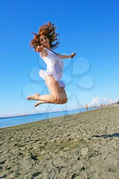 Royalty Free Photo of a Woman Jumping into the Air on the Beach