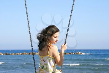 Royalty Free Photo of a Woman on a Swing by the Sea